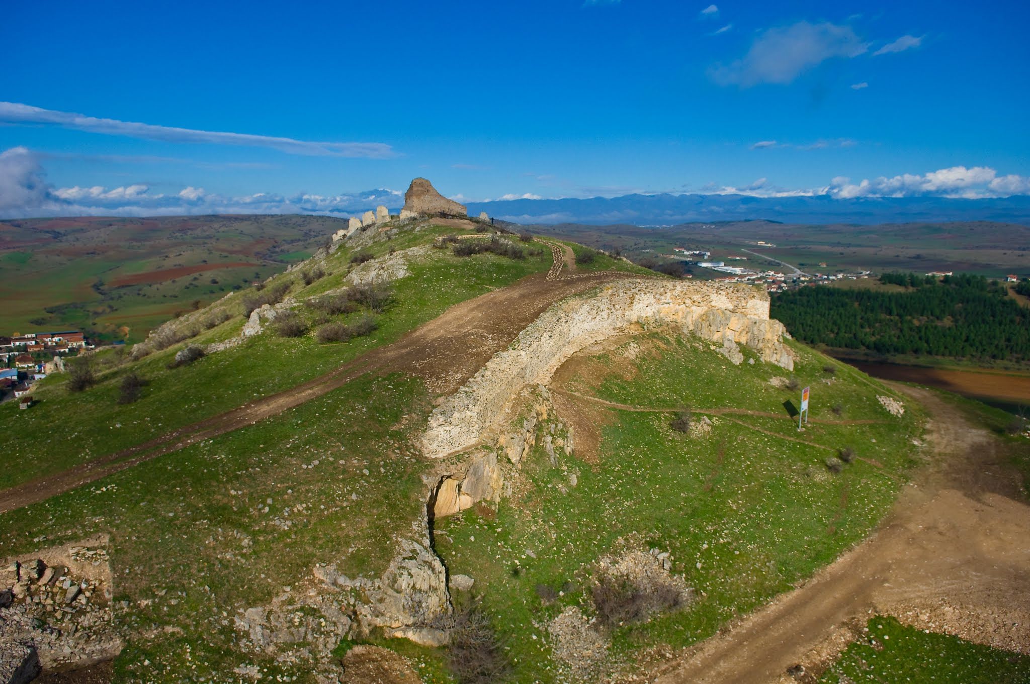 Panoramic aerial view of a hill-top historic fortification showing ruins of stone walls and surrounding countryside.
